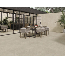 Terrasse mit Bodenfliesen, Esstisch und Stühlen vor einem Haus mit großen Fenstern.