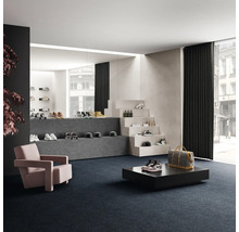 Verkaufsraum mit Schuhen auf Treppenstufen und Podesten, Sessel und Teppichboden