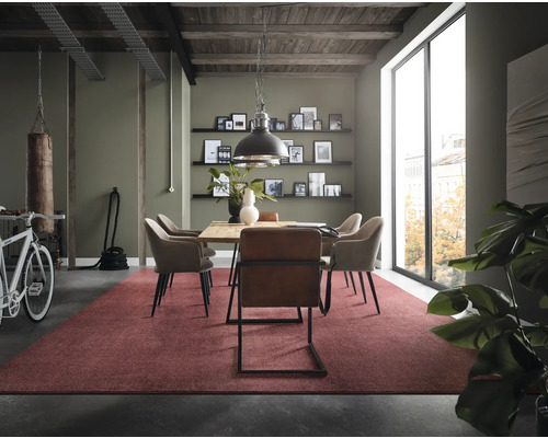 Esszimmer mit Holztisch, Stühlen, rotem Teppich und Boxsack für ein loftartiges Ambiente