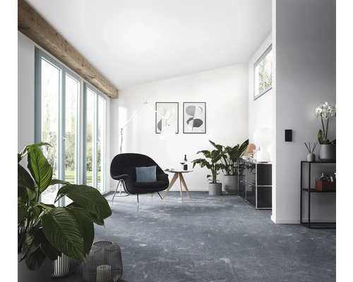 Wohnzimmer mit Sessel, Teppich und Zimmerpflanzen.