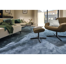 Wohnzimmer mit Sofa, Sessel, Hocker und blauem Teppich