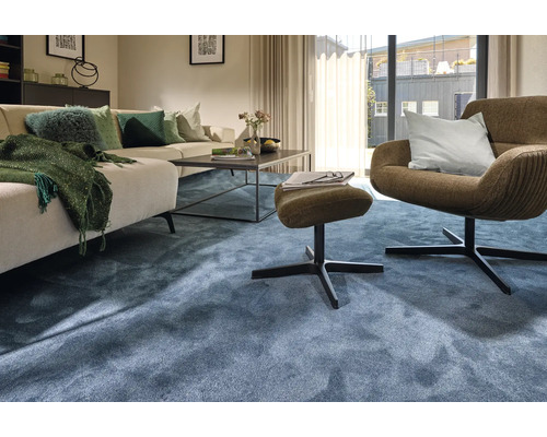 Wohnzimmer mit Sofa, Sessel, Hocker und blauem Teppich