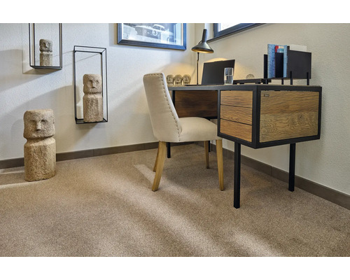 Ein Arbeitszimmer mit Schreibtisch, Stuhl und Dekorationselementen wie Skulpturen und Wandregalen.