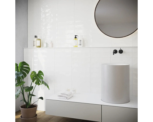 Helles Badezimmer mit weißen Fliesen, Aufsatzwaschbecken und runden Spiegel