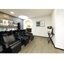 Moderner Friseursalon mit schwarzen Waschsesseln, hellem Bodenbelag in Holzoptik und weißen Wänden.