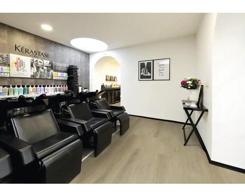 Moderner Friseursalon mit schwarzen Waschsesseln, hellem Bodenbelag in Holzoptik und weißen Wänden.