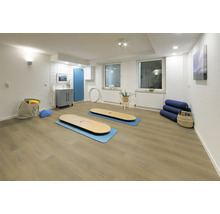 Hell gestalteter Fitnessraum mit Vinylboden in Eichenoptik, Trainingsmatten und weißer Wandgestaltung.