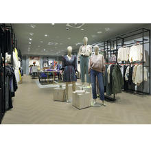 Moderner, hell gestalteter Verkaufsraum mit Bodenbelag in Fischgrät-Optik, schwarzen Kleiderständern aus Metall und bekleideten Schaufensterpuppen.