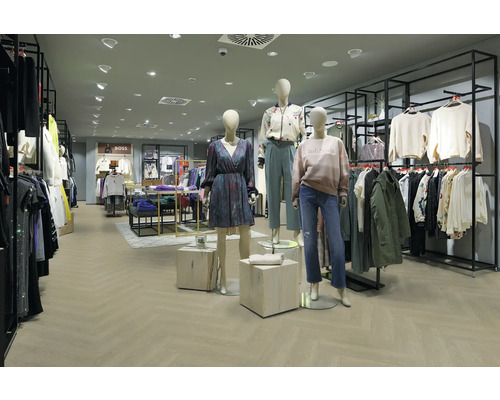 Moderner, hell gestalteter Verkaufsraum mit Bodenbelag in Fischgrät-Optik, schwarzen Kleiderständern aus Metall und bekleideten Schaufensterpuppen.