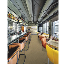 Modernes, helles Restaurant mit Bodenbelag im Fischgrätenmuster, Ledersitzhockern an der Bar und bunten Stühlen an Holztischen.