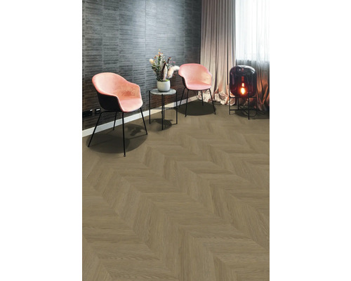 Modernes Zimmer mit Bodenbelag in Holzoptik im Fischgrätmuster, zwei rosa Samtsesseln, Beistelltisch und einer Bodenlampe aus dunklem Glas.
