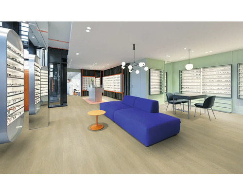 Helle, moderne Optik-Filiale mit hellem Boden in Holzoptik, blauem Sofa und weißen Verkaufsregalen für Brillen.
