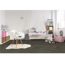 Helles Kinderzimmer mit dunklem Boden in Fischgrät-Optik, weißem Gitterbett mit Baldachin, modernem Stuhl auf Fellteppich und Aufbewahrungsboxen.