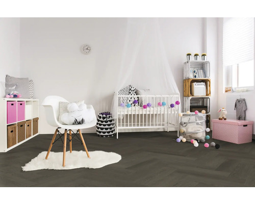 Helles Kinderzimmer mit dunklem Boden in Fischgrät-Optik, weißem Gitterbett mit Baldachin, modernem Stuhl auf Fellteppich und Aufbewahrungsboxen.