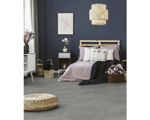 Modernes Schlafzimmer mit dunkelblauer Wand, grauem Boden in Steinoptik, Holzbett mit Paletten-Kopfteil und geflochtener Hängeleuchte.