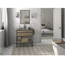 Helles Badezimmer mit Waschtisch, Spiegel und floral gemusterten Bodenfliesen.