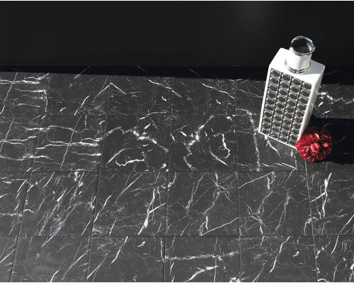 Boden mit Fliesen in Marmoroptik, darauf ein Dekorationsobjekt und eine künstliche Blume.