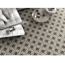 Ansicht eines Wohnzimmers mit gemusterten Bodenfliesen, Couch und Tischen.