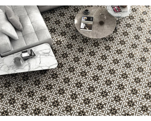 Ansicht eines Wohnzimmers mit gemusterten Bodenfliesen, Couch und Tischen.