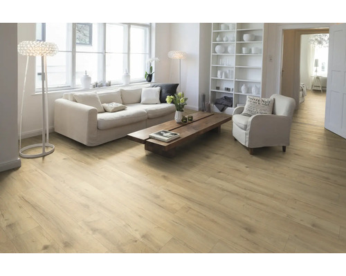 Heller Wohnraum mit Holzboden, Sofa, Sessel und Bücherregal.