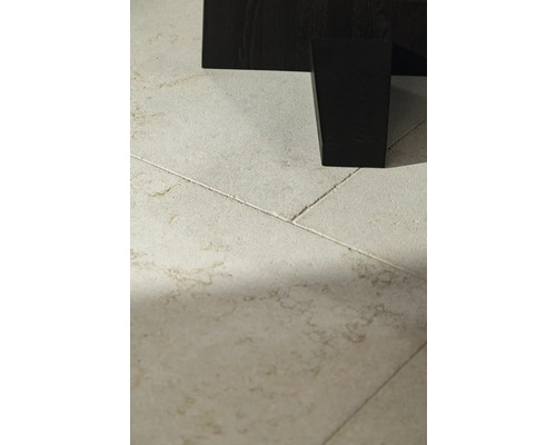 Detailaufnahme von Bodenfliesen und einem dunklen Möbelbein.