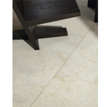 Detailaufnahme eines dunklen Holzstuhls auf einem gefliesten Boden.