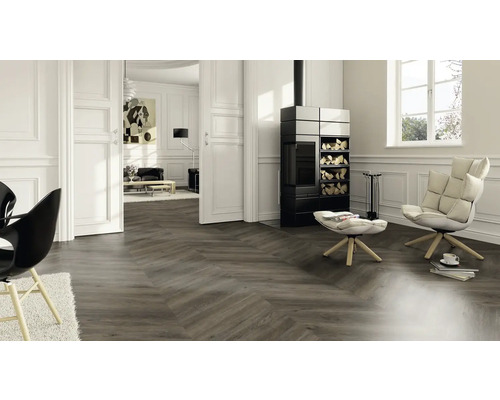 Wohnzimmer mit Fischgrätparkett, Kaminofen und Sesseln für ein stilvolles Ambiente