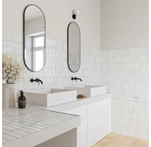 Helles modernes Badezimmer mit zwei weißen Aufsatzbecken, schwarzen Wandarmaturen, ovalen Spiegeln und kleinen weißen Rechteckfliesen.
