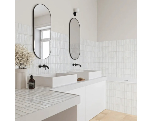 Helles modernes Badezimmer mit zwei weißen Aufsatzbecken, schwarzen Wandarmaturen, ovalen Spiegeln und kleinen weißen Rechteckfliesen.