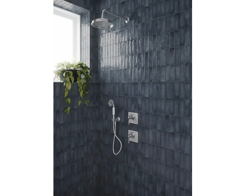 Dunkelblaue glänzende Wandfliesen vertikal verlegt in einer Dusche mit Regendusche, Handbrause und Chromarmaturen.