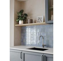 Moderne Küche mit blauem Fliesenspiegel, glänzenden quadratischen Wandfliesen, hellem Holzregal, Chrom-Armatur und schwarzem Einbaubecken.