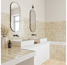 Helles Badezimmer mit zwei weißen Aufsatzwaschbecken, schwarzen Wandarmaturen, ovalen Spiegeln und beigen quadratischen Wandfliesen.