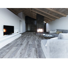 Großzügiges Wohnzimmer mit grauem Laminatboden in Holzoptik, modernem Steinkamin, grauen Sofas und Dachschräge mit Holzbalken.