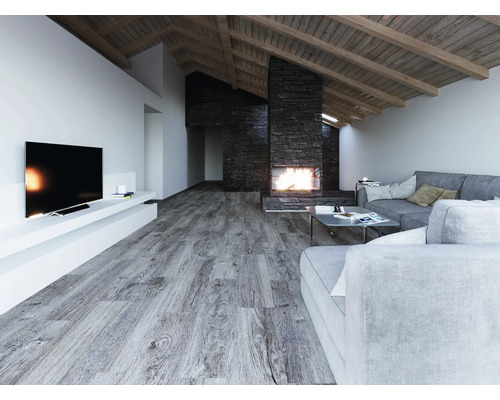 Großzügiges Wohnzimmer mit grauem Laminatboden in Holzoptik, modernem Steinkamin, grauen Sofas und Dachschräge mit Holzbalken.