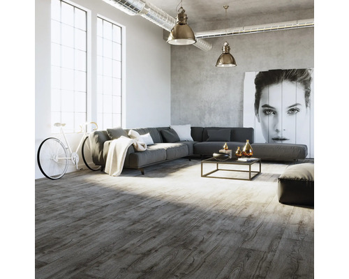 Modernes Wohnzimmer im Loft-Stil mit grauem Bodenbelag in Holzoptik, großem Ecksofa und Sichtbetonwand.