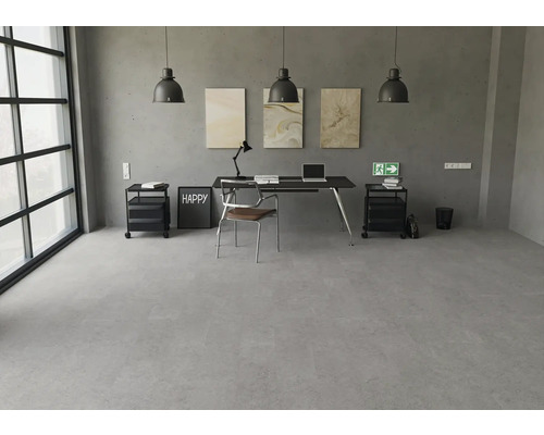 Moderner Arbeitsbereich mit grauem Bodenbelag in Betonoptik, schwarzem Schreibtisch und industriellen Pendelleuchten vor einer Betonwand.