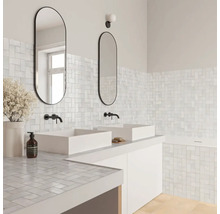 Modernes helles Badezimmer mit weißen Mosaikfliesen an Wänden und Waschtisch, zwei weißen Aufsatzbecken, schwarzen Armaturen und ovalen Spiegeln.