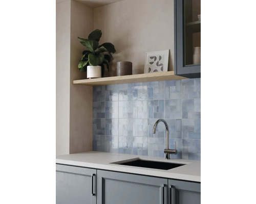 Moderne Küche mit hellblauen Wandfliesen hinter einer Spüle mit Chromarmatur und einem Holzregal darüber.