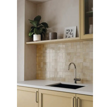 Hellbeige Wandfliesen in Flechtoptik in einer modernen Küche mit hellem Holzregal, Chrom-Armatur und schwarzem Spülbecken.