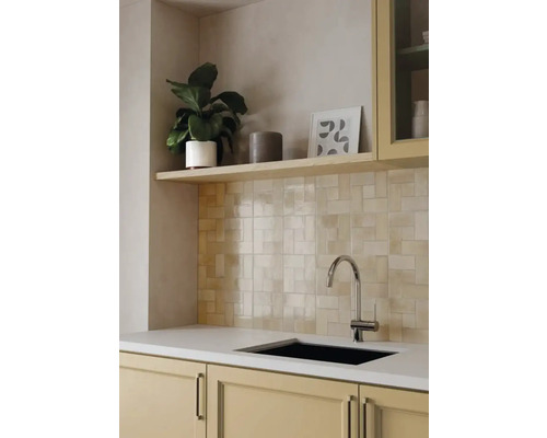 Hellbeige Wandfliesen in Flechtoptik in einer modernen Küche mit hellem Holzregal, Chrom-Armatur und schwarzem Spülbecken.