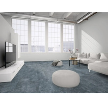 Moderner Wohnraum mit blau-grauem Strukturboden, weißem Sofa, großen Fenstern und industriellem Loft-Stil.