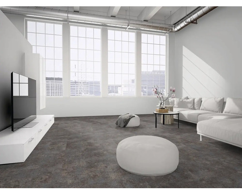 Moderner Loft-Wohnraum mit dunklem strukturiertem Boden, großen Sprossenfenstern, weißem Sofa und Deckenrohren. Hell und weitläufig.