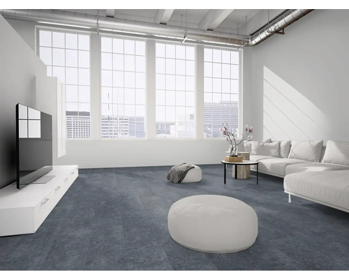 Moderner, heller Wohnraum im Loft-Stil mit großflächigem dunkelblauem Bodenbelag, großen Fenstern, weißem Sofa und freiliegenden Lüftungsrohren.