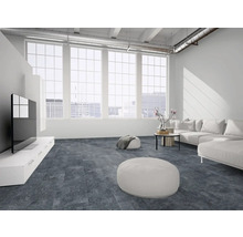 Moderner Wohnbereich im Loft-Stil mit großflächigen Fenstern, weißem Sofa und strukturiertem Bodenbelag in dunkler Steinoptik.