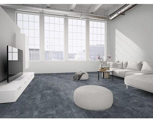 Moderner Wohnbereich im Loft-Stil mit großflächigen Fenstern, weißem Sofa und strukturiertem Bodenbelag in dunkler Steinoptik.