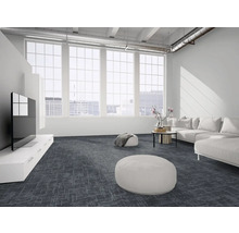 Moderner, heller Wohnraum mit dunkelgrauen gemusterten Teppichfliesen, großem weißem Sofa, Sitzpuffs und großen Fenstern im Loft-Stil.