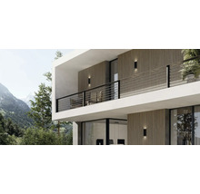 Modernes Haus mit Außenwandleuchten und Balkon vor Bergkulisse.