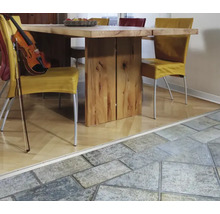 Übergangsprofil zwischen Holzparkett und Steinfliesen in einem hellen Esszimmer mit Holztisch und Stühlen.