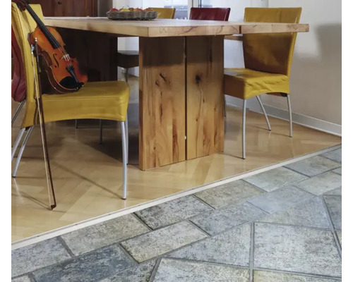 Übergangsprofil zwischen Holzparkett und Steinfliesen in einem hellen Esszimmer mit Holztisch und Stühlen.