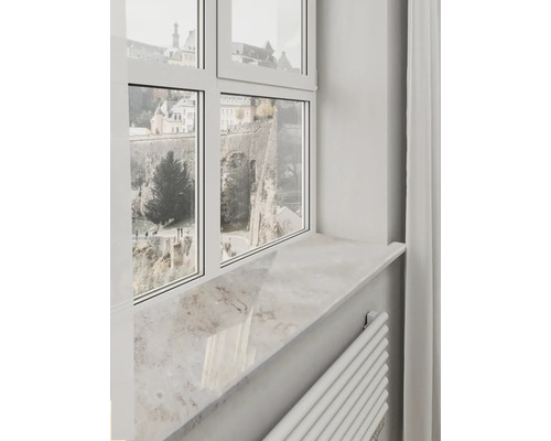 Helle Fensterbank in Natursteinoptik unter einem weißen Fensterrahmen mit Ausblick auf historische Mauern.